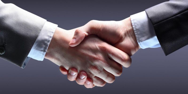 Hai người mặc vest bắt tay trên nền xám, tượng trưng cho hợp tác đại lý 8xbet