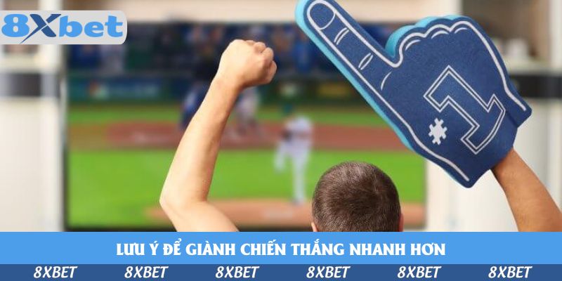 Cổ động viên giơ nắm tay và găng ngón trỏ xốp màu xanh trước màn hình đang chiếu trận bóng chày