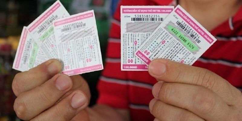 Hai bàn tay cầm nhiều thẻ cào điện thoại mệnh giá 100.000đ đã cào lộ mã số và số seri
